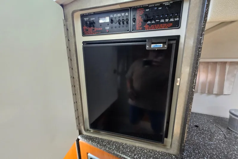 Slide: The Image of Control panel and refrigerator inside a 2005 Formula 330 Sun Sport boat. - 14