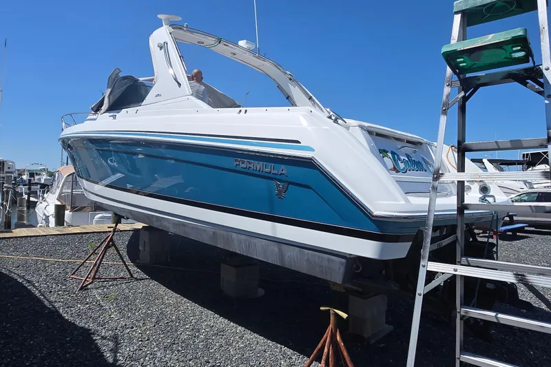 Slide: The Image of 2005 Formula 330 Sun Sport boat on dry dock with blue and white exterior. - 25