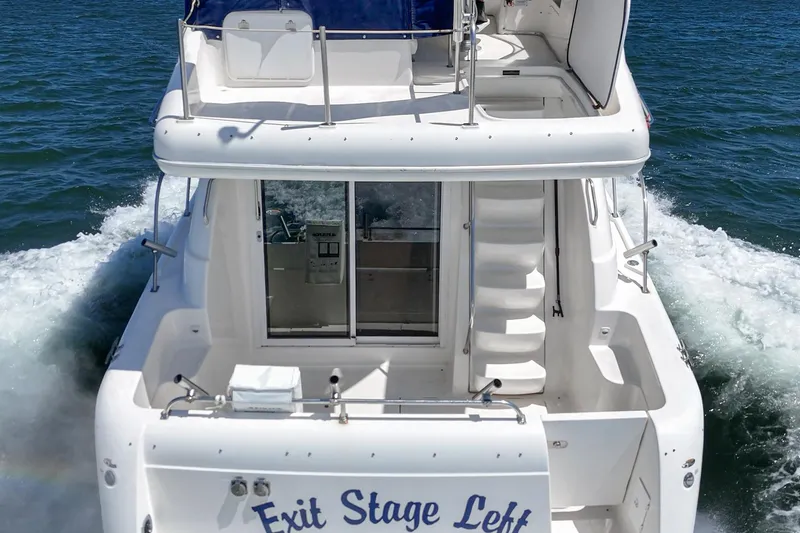 Slide: The Image of 2003 Meridian 341 Sedan yacht cruising on water, rear view with "Exit Stage Left" text. - 22