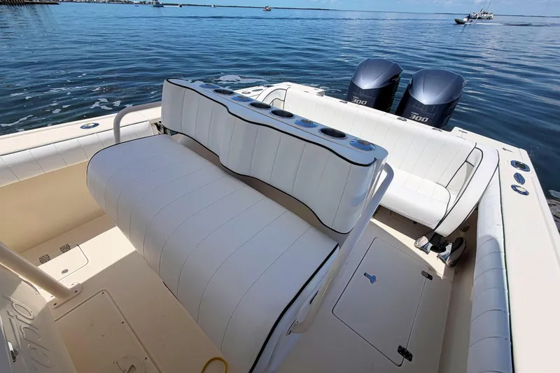 Slide: The Image of 2003 Intrepid 322 Cuddy boat interior with seating and dual outboard motors on calm water. - 14