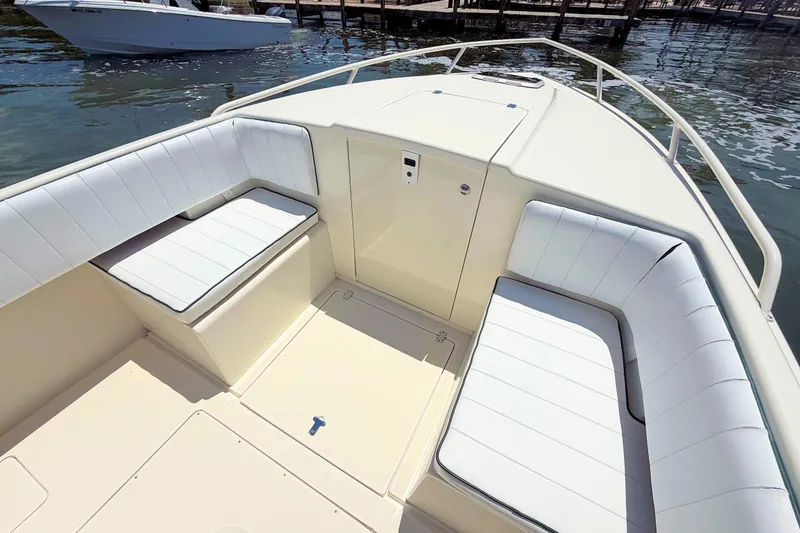 Slide: The Image of 2003 Intrepid 322 Cuddy boat interior with white cushioned seating and sleek design. - 16