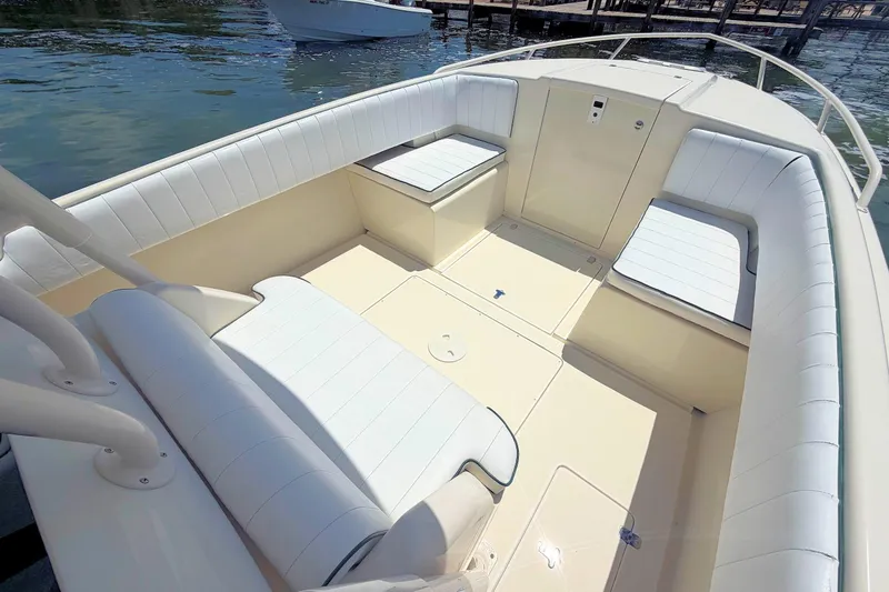 Slide: The Image of 2003 Intrepid 322 Cuddy boat interior with white cushioned seating and open deck. - 17