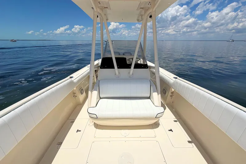 Slide: The Image of 2003 Intrepid 322 Cuddy boat interior with white seating, calm ocean, and blue sky. - 18