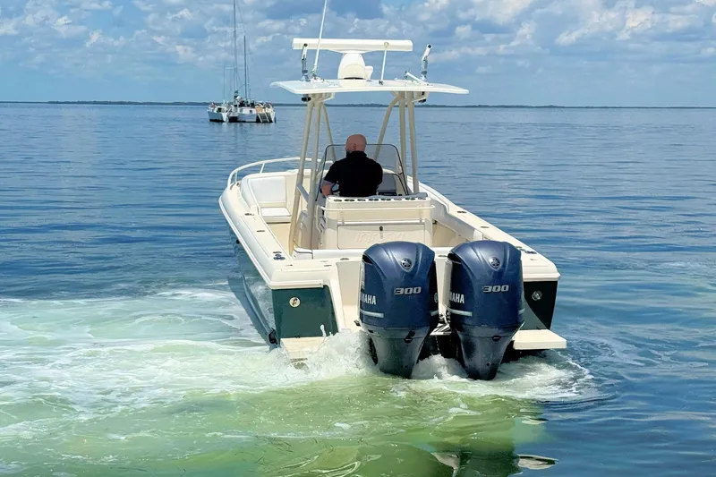 Slide: The Image of 2003 Intrepid 322 Cuddy boat with twin Yamaha engines cruising on calm waters. - 6