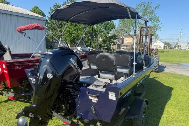 Slide: The Image of 2026 Tracker Pro Guide V-16 SC boat with Mercury engine, parked on grass. - 7
