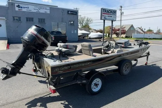 The Image of 1999 Tracker Pro Team 165 boat with motor on trailer, parked outside dealership. - 2