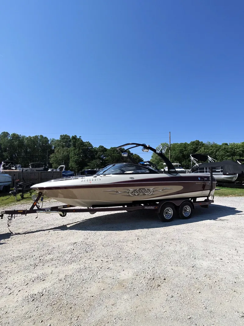 The Image of 2005 Malibu XTI boat on trailer under clear blue sky. - 1