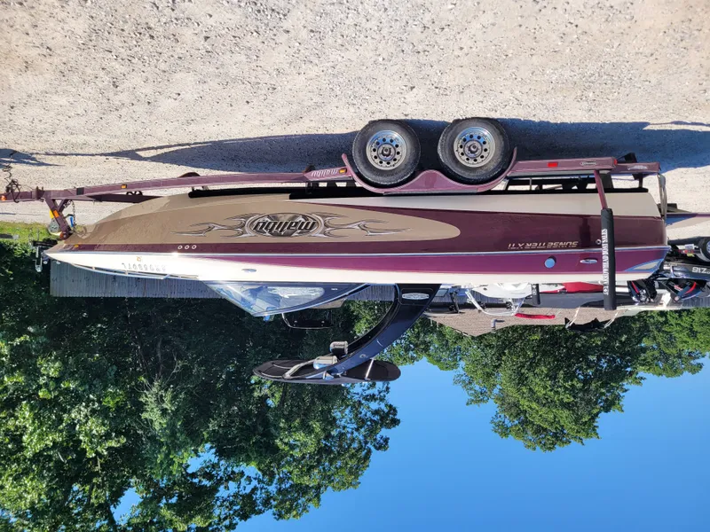 Slide: The Image of 2005 Malibu XTI boat on trailer, parked outdoors. - 12