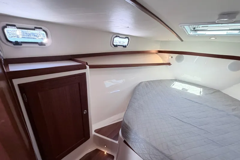 Slide: The Image of 2025 NorthCoast 415 HT cabin interior with bed, wooden cabinet, and windows. - 24