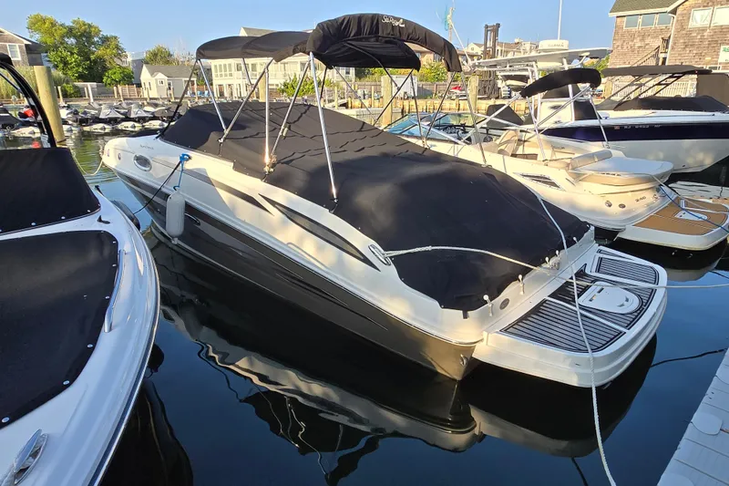 Slide: The Image of 2012 Sea Ray 260 Sundeck boat docked with black cover and canopy. - 2