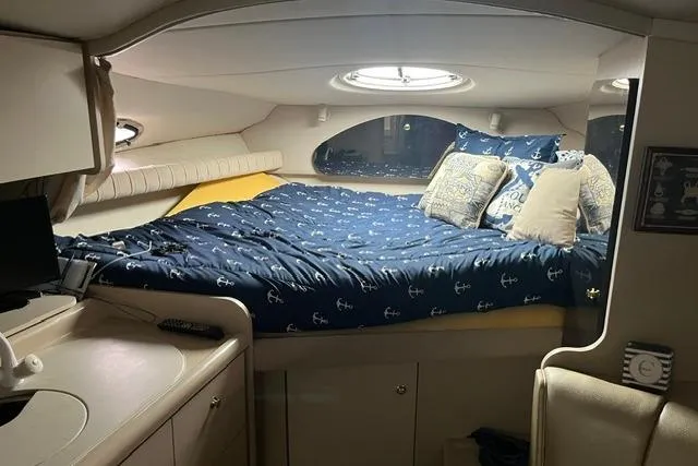 Slide: The Image of 1999 Cruisers Yachts 3075 Express cabin with cozy bed and nautical-themed bedding. - 10
