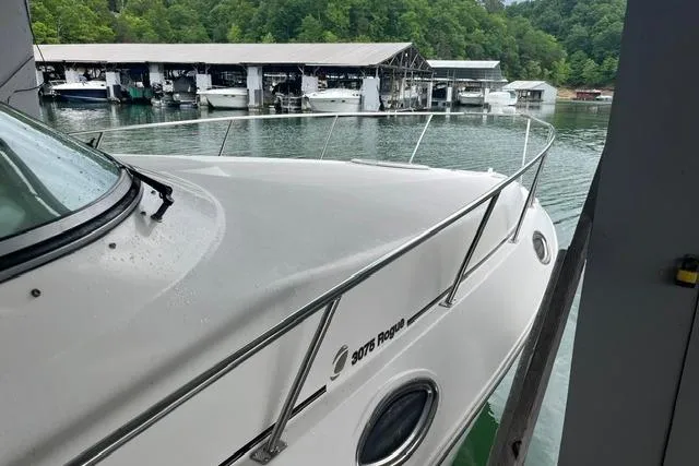 Slide: The Image of 1999 Cruisers Yachts 3075 Express docked near marina with lush green backdrop. - 3