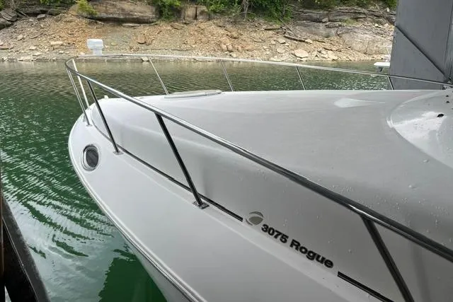 Slide: The Image of 1999 Cruisers Yachts 3075 Express boat docked by rocky shoreline. - 4