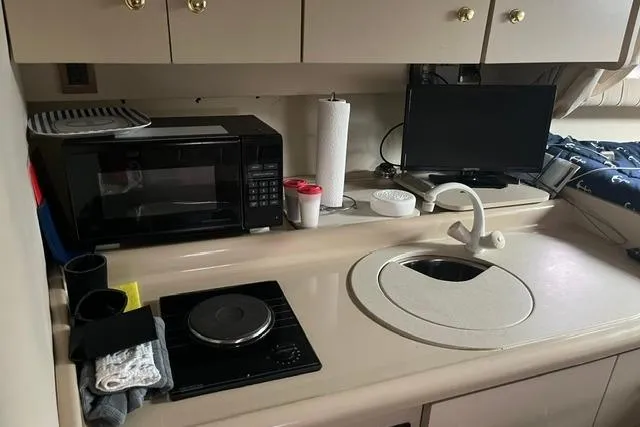 Slide: The Image of 1999 Cruisers Yachts 3075 Express kitchen with microwave, stove, sink, and TV. - 7