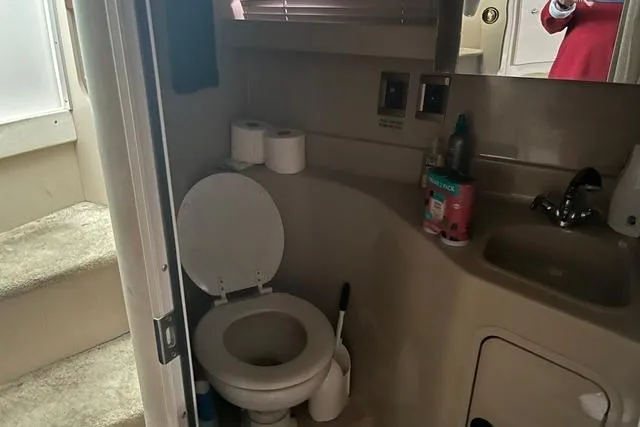 Slide: The Image of 1999 Cruisers Yachts 3075 Express bathroom with toilet, sink, and toiletries. - 9