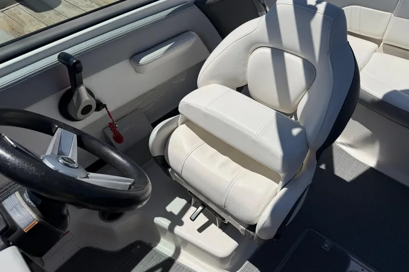 Slide: The Image of 2019 Chaparral 21 H2O Sport OB boat interior with steering wheel and white captain's chair. - 15