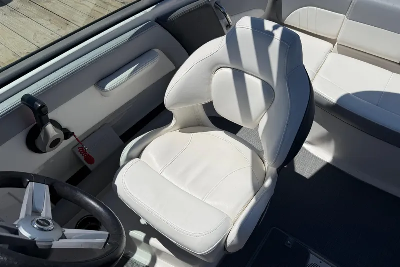 Slide: The Image of 2019 Chaparral 21 H2O Sport OB boat interior with white captain's chair and steering wheel. - 16