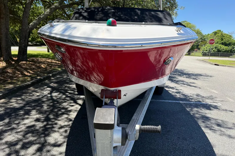 Slide: The Image of 2019 Chaparral 21 H2O Sport OB boat on trailer, red hull, parked outdoors. - 8