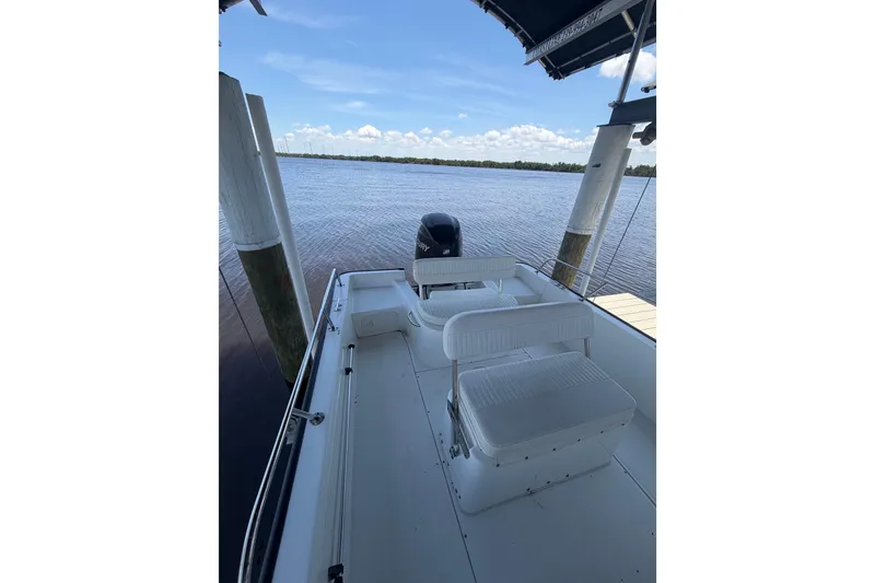 Slide: The Image of 2012 Boston Whaler 190 Montauk boat docked by serene waters under a clear sky. - 11