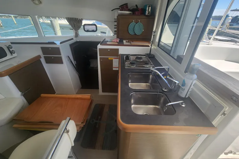 Slide: The Image of Interior of 2019 Lagoon 380 catamaran featuring a compact kitchen with dual sinks and stove. - 14