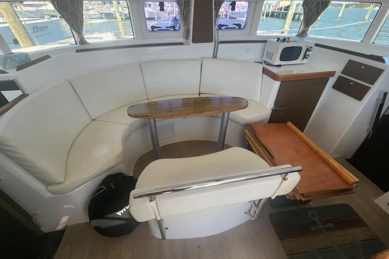 Slide: The Image of Interior of 2019 Lagoon 380 catamaran with white seating, wooden table, and nautical decor. - 15