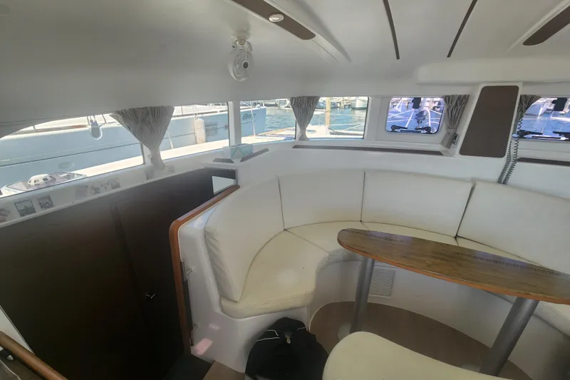 Slide: The Image of Interior of 2019 Lagoon 380 catamaran with white seating and wooden table. - 16