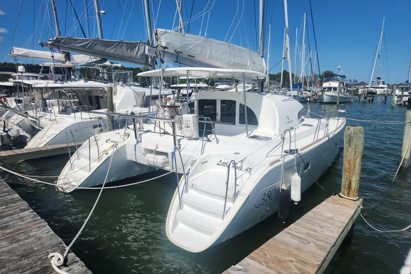 Slide: The Image of 2019 Lagoon 380 catamaran docked at a marina under clear blue skies. - 2