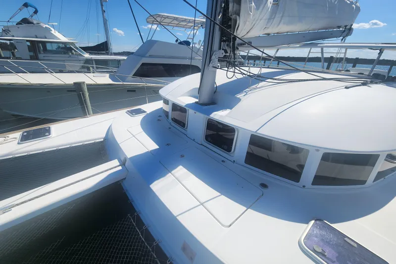 Slide: The Image of 2019 Lagoon 380 catamaran docked, showcasing sleek design and spacious deck under clear skies. - 35