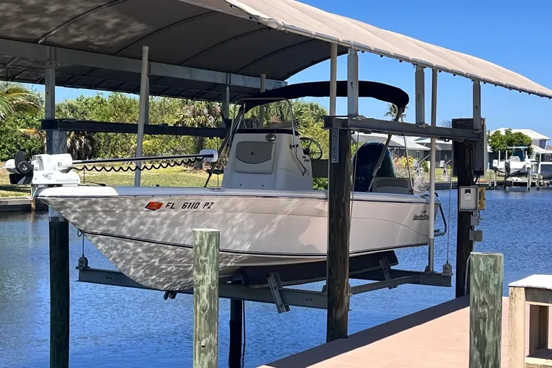 Slide: The Image of 2016 NauticStar 2110 Sport boat on lift by waterfront dock. - 1