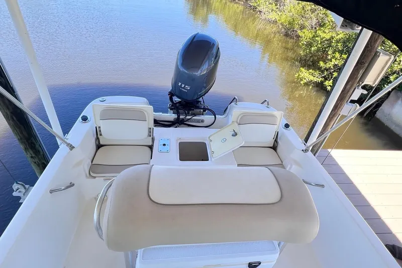 Slide: The Image of 2016 NauticStar 2110 Sport boat interior with Yamaha 115 engine, docked on calm water. - 15