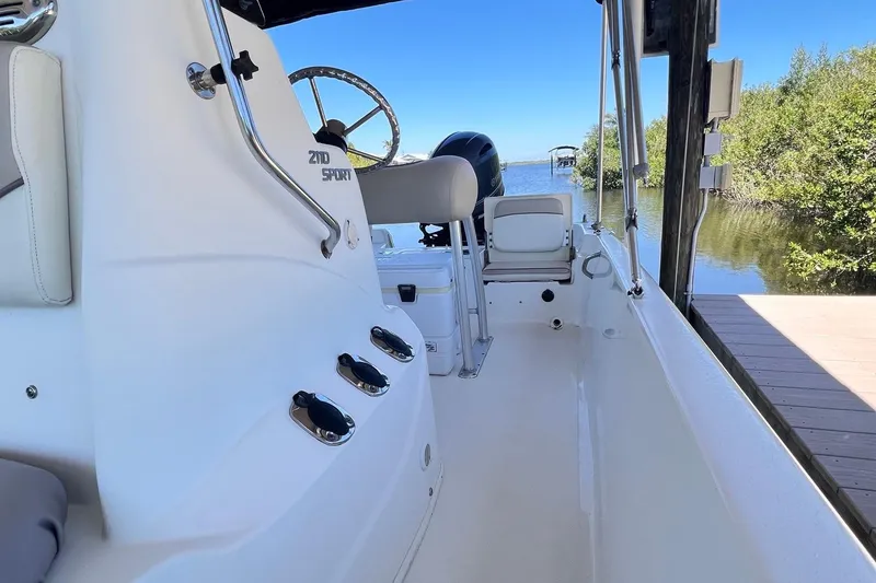 Slide: The Image of 2016 NauticStar 2110 Sport boat interior, featuring steering wheel and seating, docked by a scenic lake. - 5