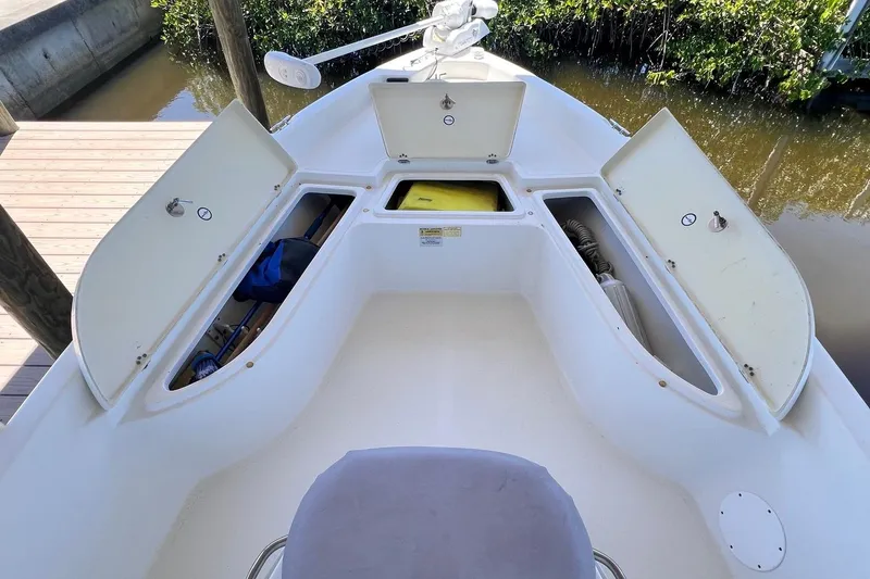 Slide: The Image of 2016 NauticStar 2110 Sport boat with open storage compartments, docked by water. - 6