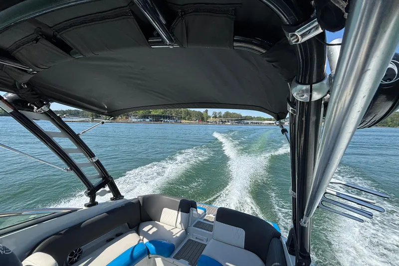Slide: The Image of 2022 Crownline 265 SS SURF boat cruising on a sunny lake, leaving a wake behind. - 1