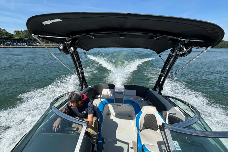 Slide: The Image of 2022 Crownline 265 SS SURF boat cruising on a sunny lake with a canopy. - 2