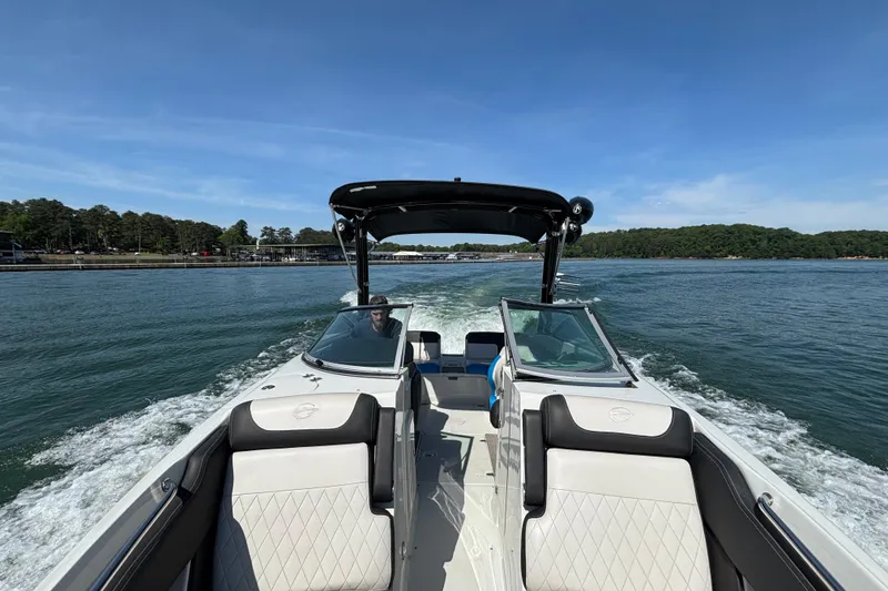 Slide: The Image of 2022 Crownline 265 SS SURF boat cruising on a scenic lake under clear blue skies. - 3