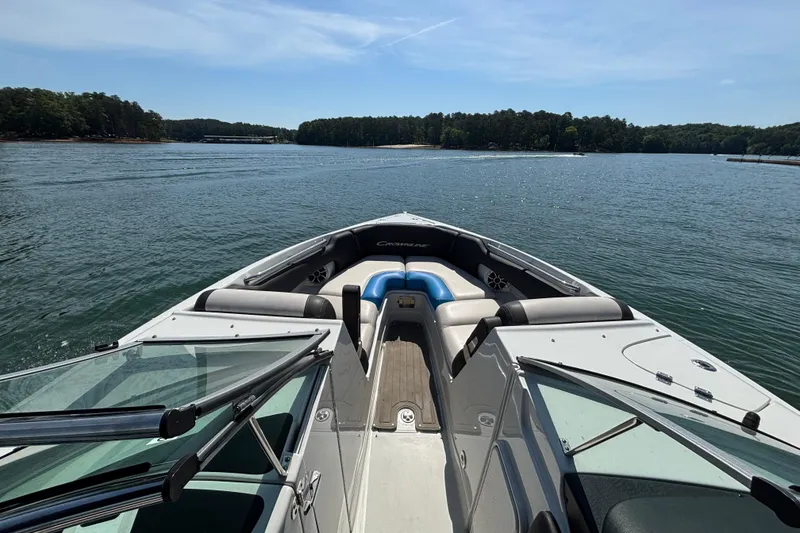 Slide: The Image of 2022 Crownline 265 SS SURF boat on a serene lake with lush forest backdrop. - 5