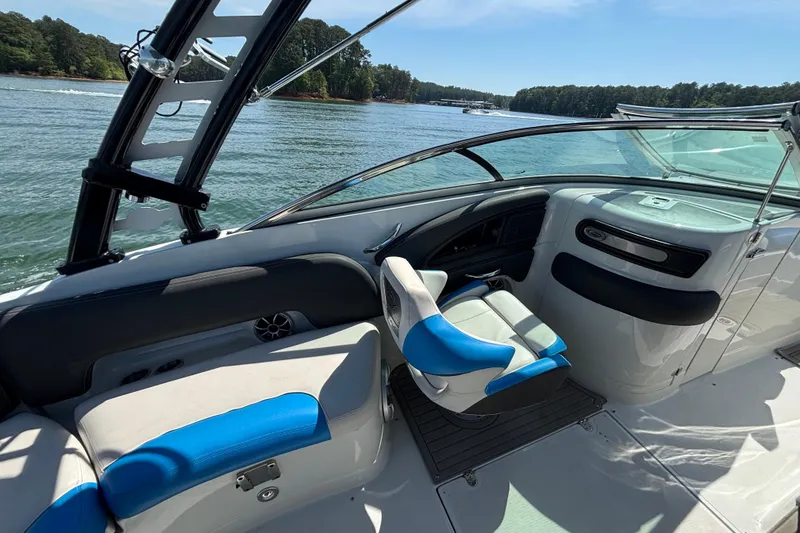 Slide: The Image of 2022 Crownline 265 SS SURF boat interior with blue and white seating on a sunny lake. - 8