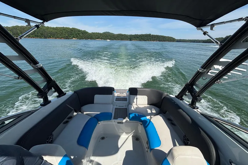 Slide: The Image of 2022 Crownline 265 SS SURF boat cruising on a scenic lake with lush green shoreline. - 9
