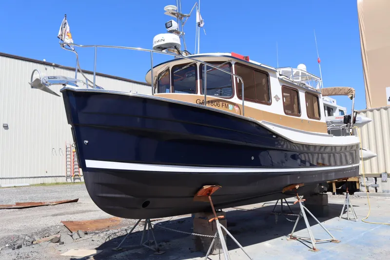 Slide: The Image of 2015 Ranger Tugs R-27 boat on stands, blue hull, outdoor storage. - 2