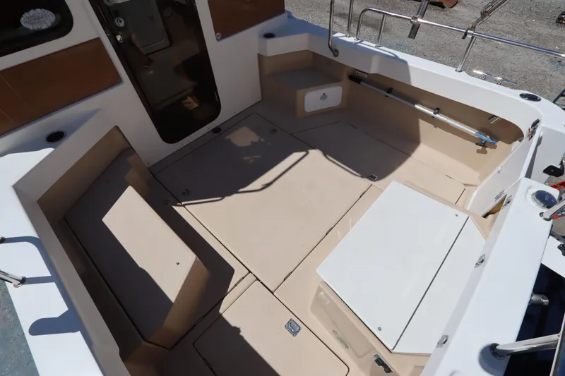 Slide: The Image of 2015 Ranger Tugs R-27 boat cockpit with beige seating and storage compartments. - 20