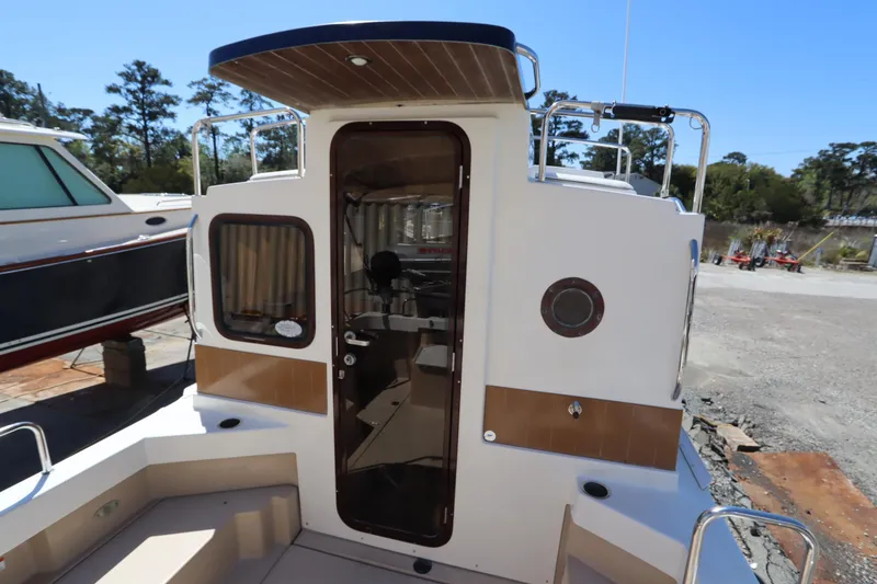 Slide: The Image of 2015 Ranger Tugs R-27 boat stern view with open cabin door, docked outdoors. - 35