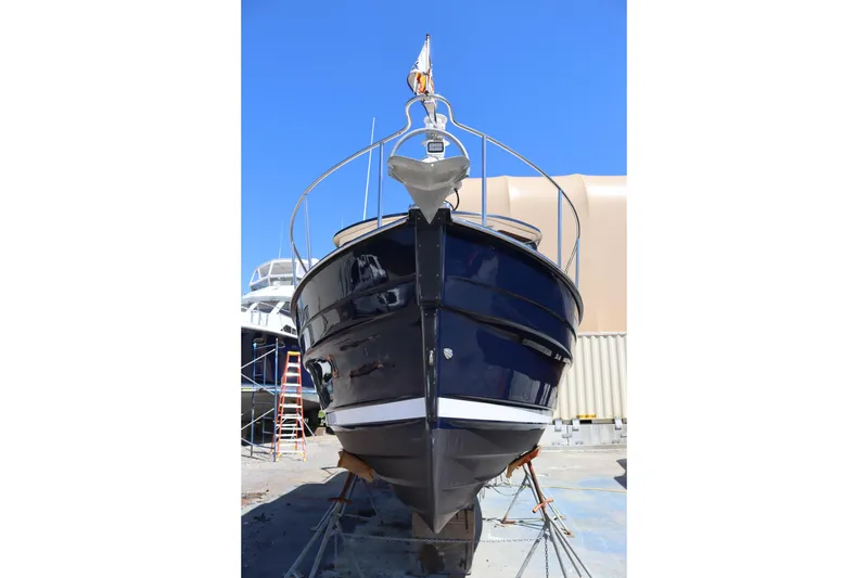 Slide: The Image of 2015 Ranger Tugs R-27 boat on dry dock, viewed from the front, under clear blue sky. - 4