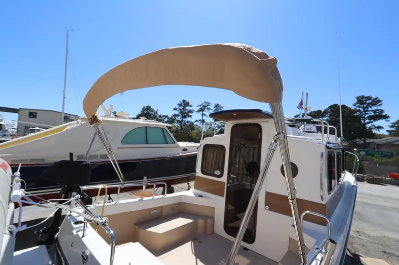Slide: The Image of 2015 Ranger Tugs R-27 boat with tan canopy, docked under clear blue sky. - 49