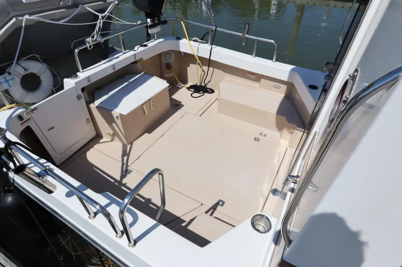 Slide: The Image of 2015 Ranger Tugs R-27 boat deck with seating and storage, docked by the water. - 51