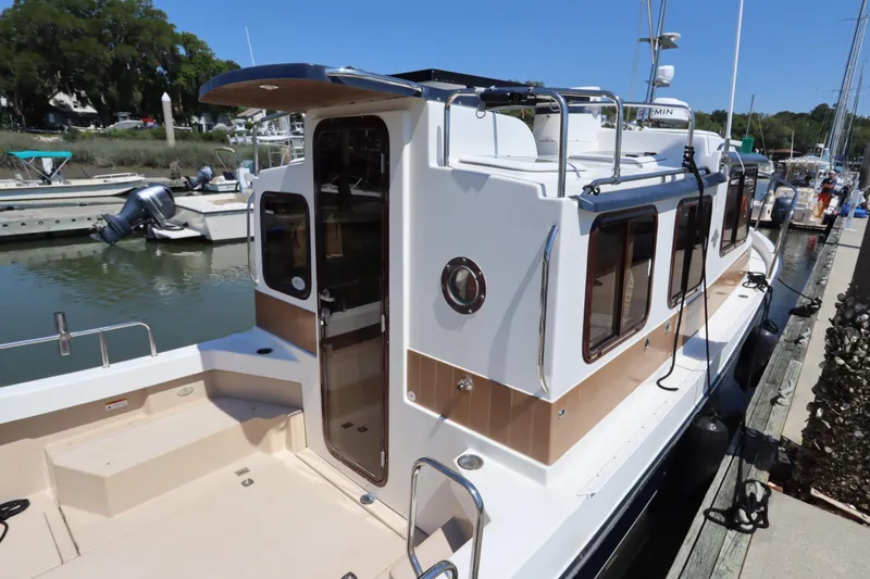 Slide: The Image of 2015 Ranger Tugs R-27 docked at marina, showcasing sleek design and spacious deck. - 53