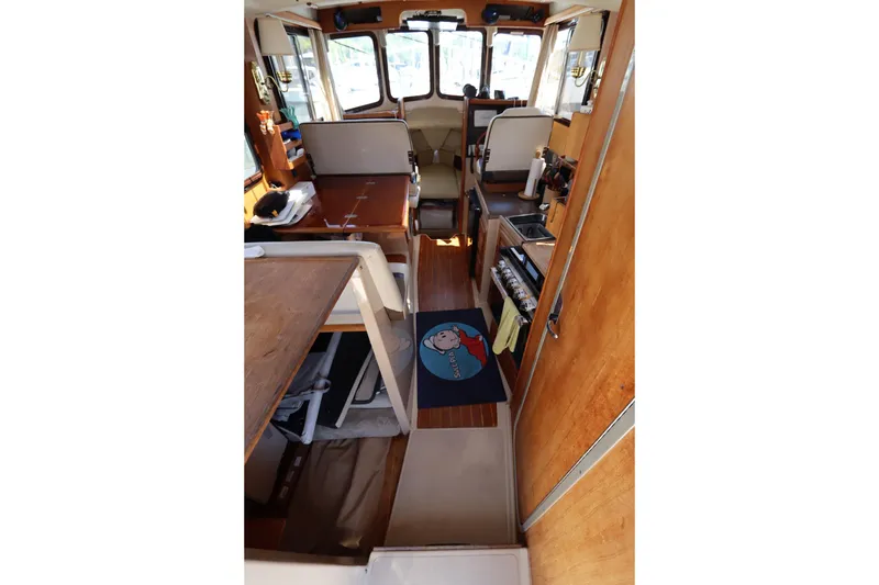 Slide: The Image of Interior of 2015 Ranger Tugs R-27 boat, featuring cozy seating and wooden finishes. - 65
