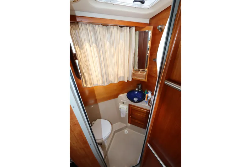 Slide: The Image of Compact bathroom in 2015 Ranger Tugs R-27 boat with sink, toilet, and wooden cabinetry. - 75