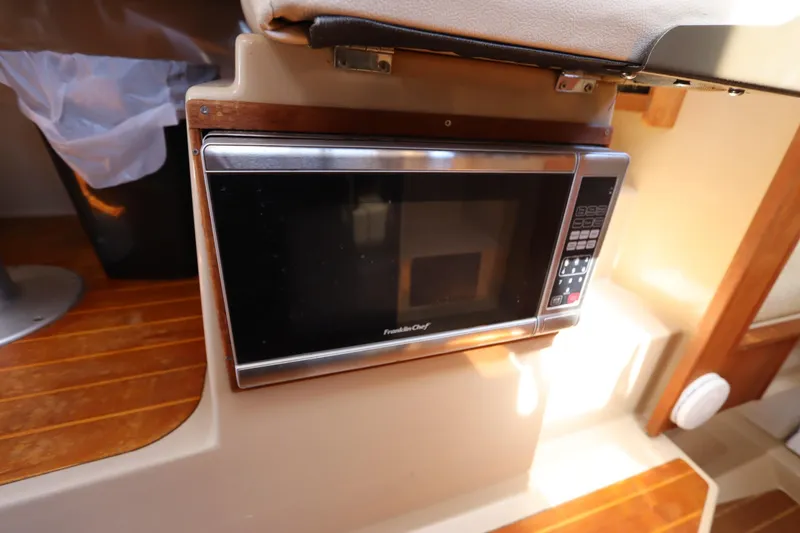 Slide: The Image of Microwave in 2015 Ranger Tugs R-27 boat interior, featuring wooden flooring. - 95