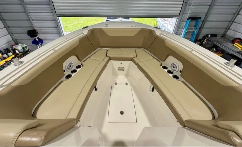 Slide: The Image of 2018 Sailfish 325 DC boat interior with tan seating and speakers in a garage. - 11