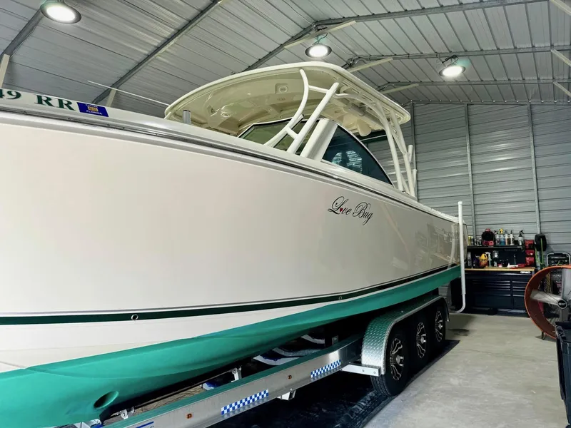 Slide: The Image of 2018 Sailfish 325 DC boat in a garage, on a trailer, under bright lighting. - 13
